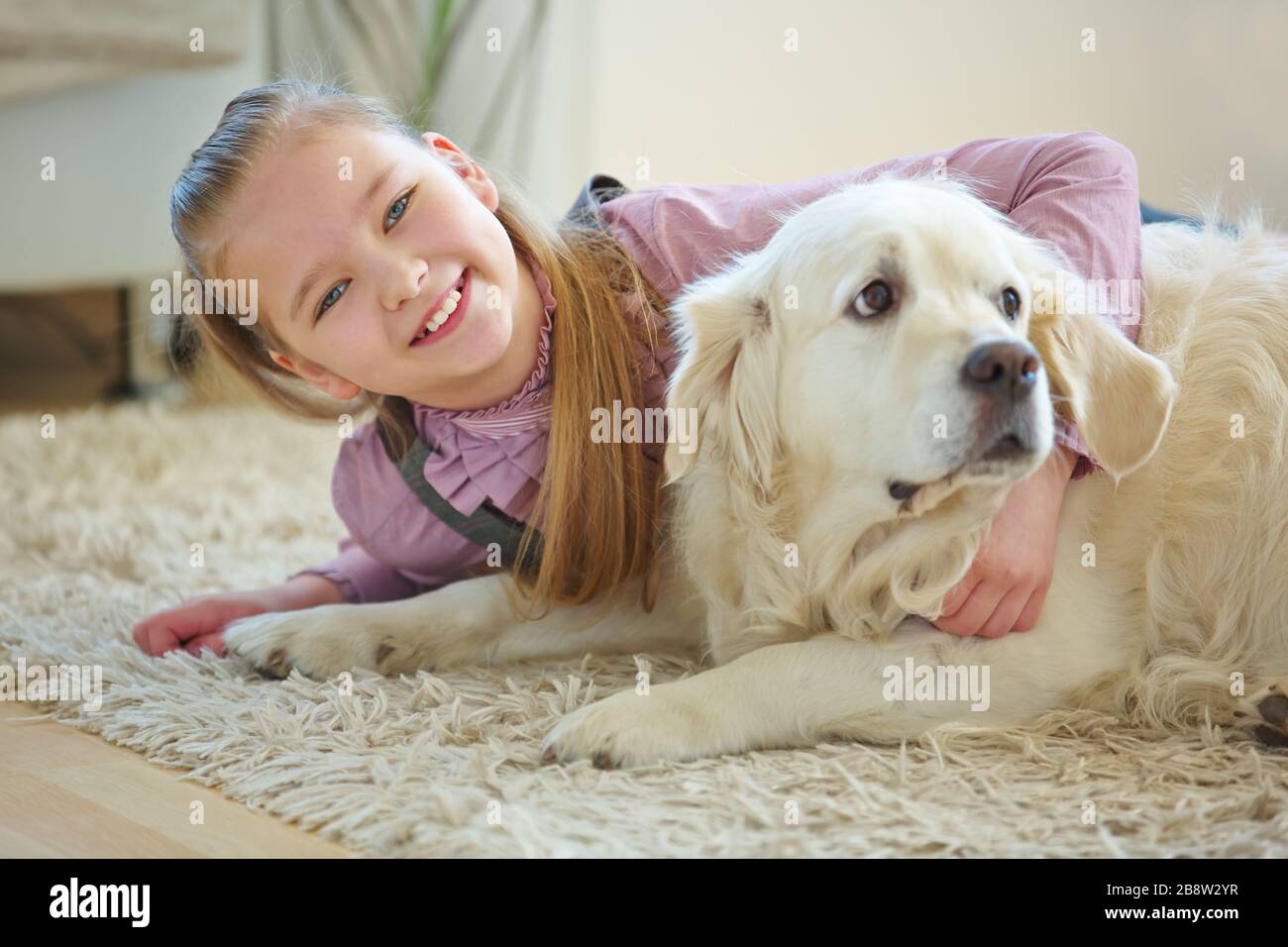 Glückliches Kind umarmt Hund als Haustier zu Hause Stockfoto