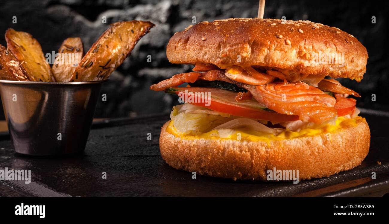 Appetitlicher Fischburger mit roten Fischfleischstücken auf Backstein-Wandhintergrund. Stock-Fotoburger mit Fischfüllung. Stockfoto