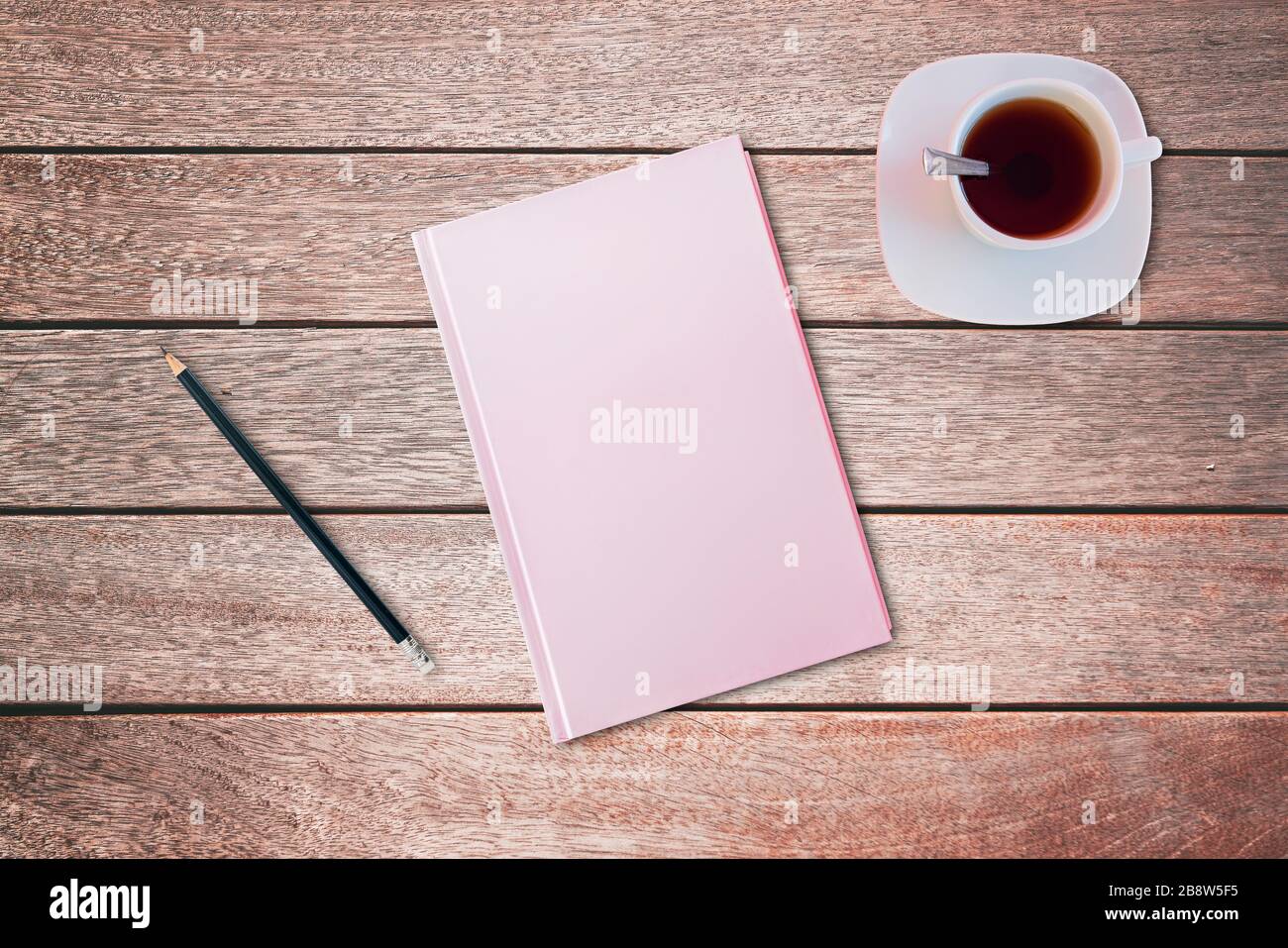 Bleistift und ein pinkfarbenes Notizbuch auf Holztisch. Vogelperspektive, Mock-up-Konzept Stockfoto