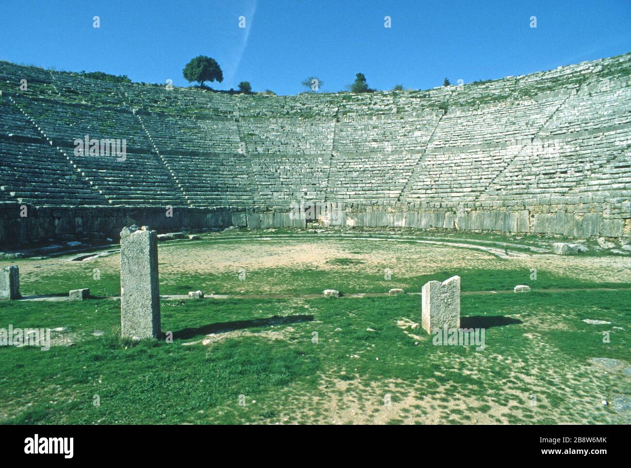 Das antike griechische Theater in Dodoni, Ioannina, Epirus, Griechenland, von den Darstellern aus gesehen, zeigt geschwungene Reihen von Steinsitzen, die auf die Bühne hinunter schauen und zu jeder Ebene hinaufsteigen. Blauer Himmel im Hintergrund. Dodoni ist eines von 15 antiken griechischen Theatern mit vorläufigem Status als UNESCO-Weltkulturerbe. Stockfoto