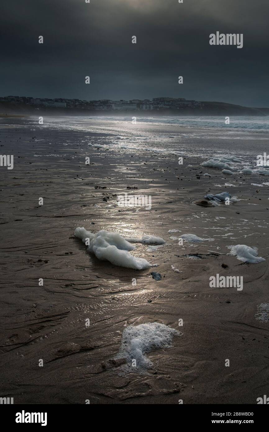 Spume wusch sich bei einer sich zurückziehenden Flut an einem kalten, kühlen Fistral Beach in Newquay in Cornwall im Vereinigten Königreich. Stockfoto