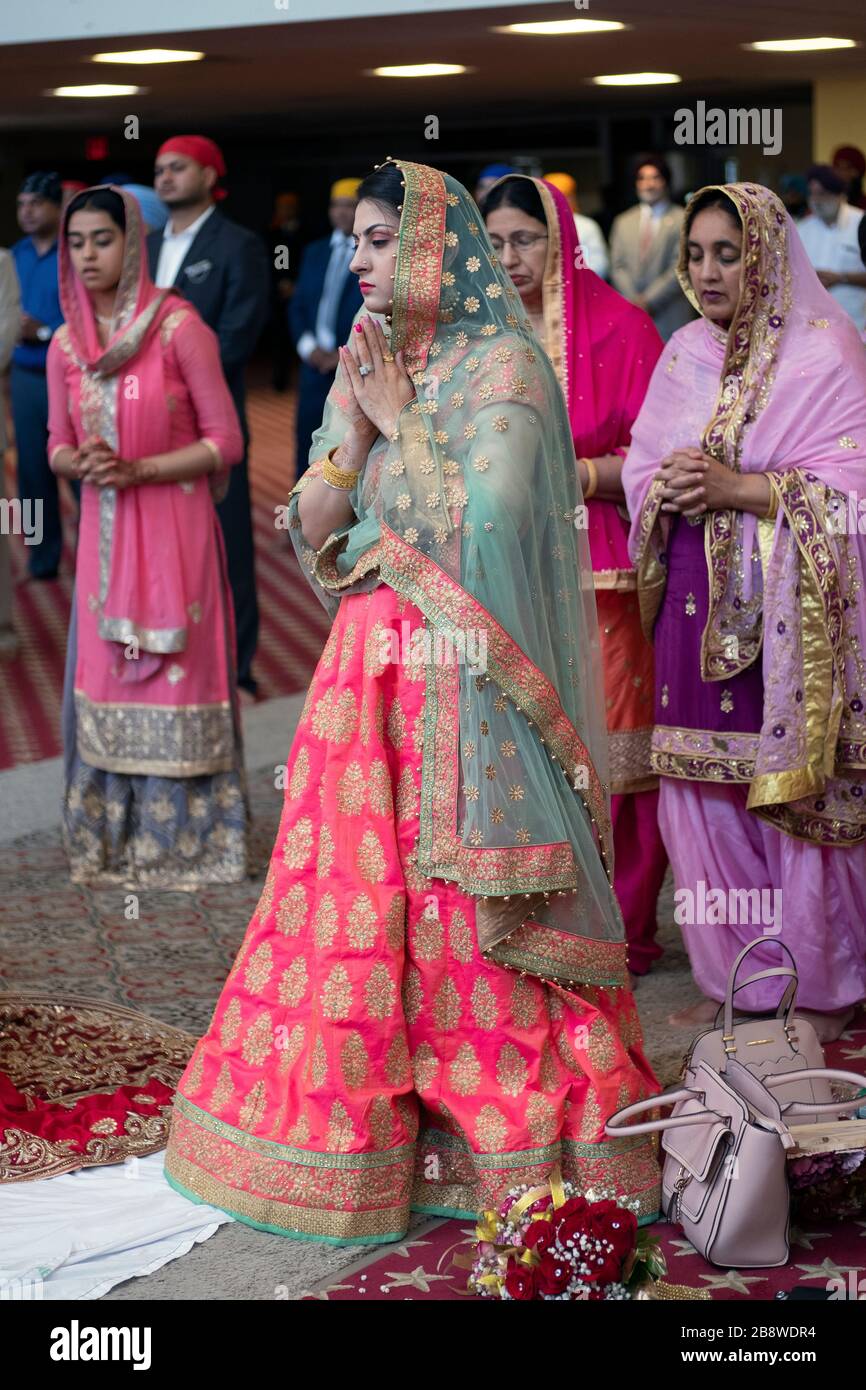 Fromme Sikh-Frauen in schönen Saris beten und meditieren vor einer Hochzeitsfeier in einem Tempel in Queens, New York City. Stockfoto