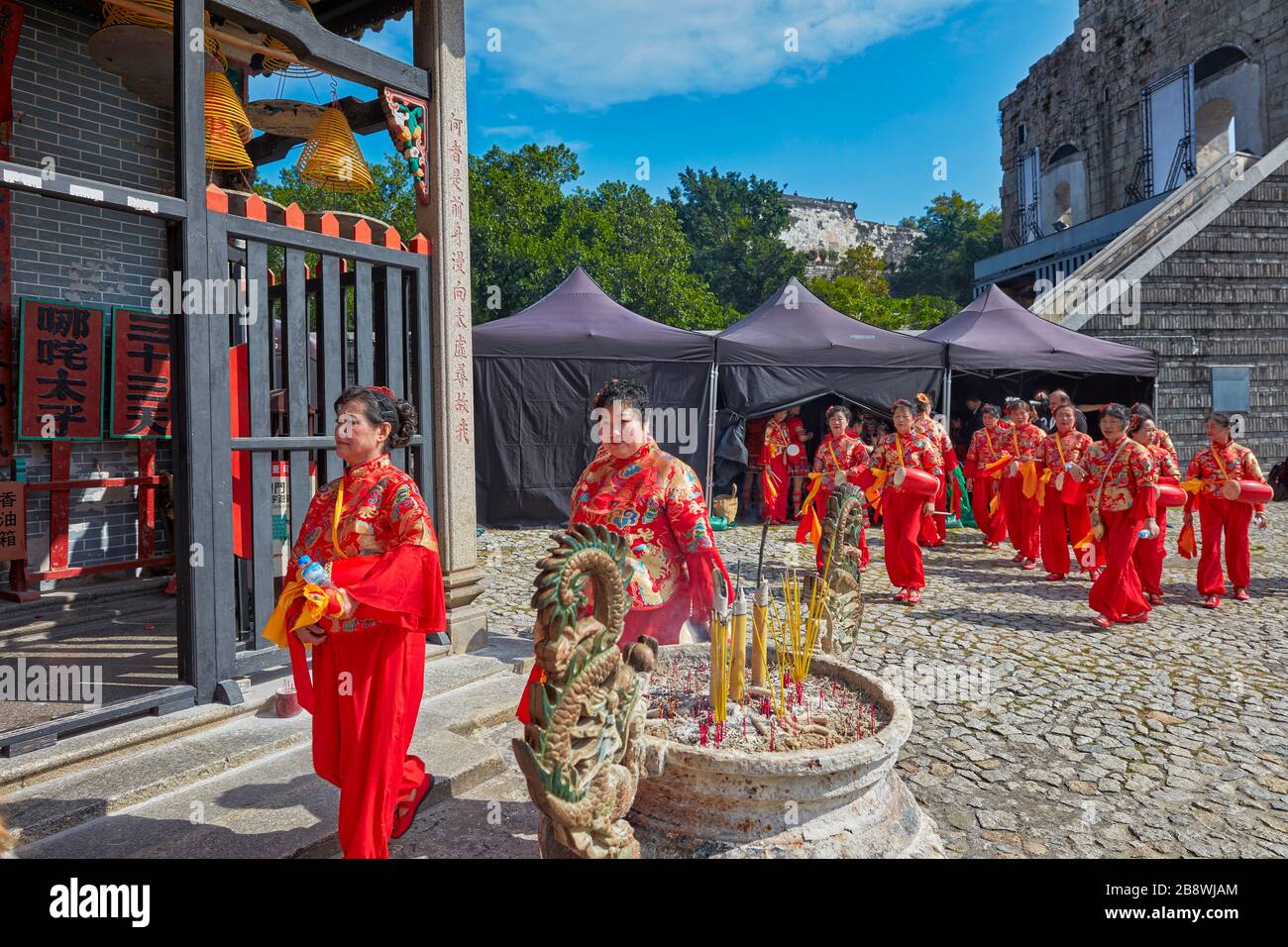 Einheimische Frauen in roten Trachten, die am Na Tcha Tempel spazieren gehen. Macau, China. Stockfoto
