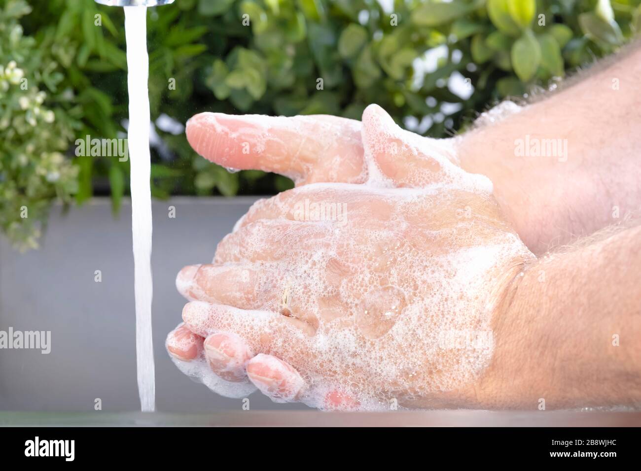 Schäumende männliche Hände waschen mit fließendem Wasser Stockfoto