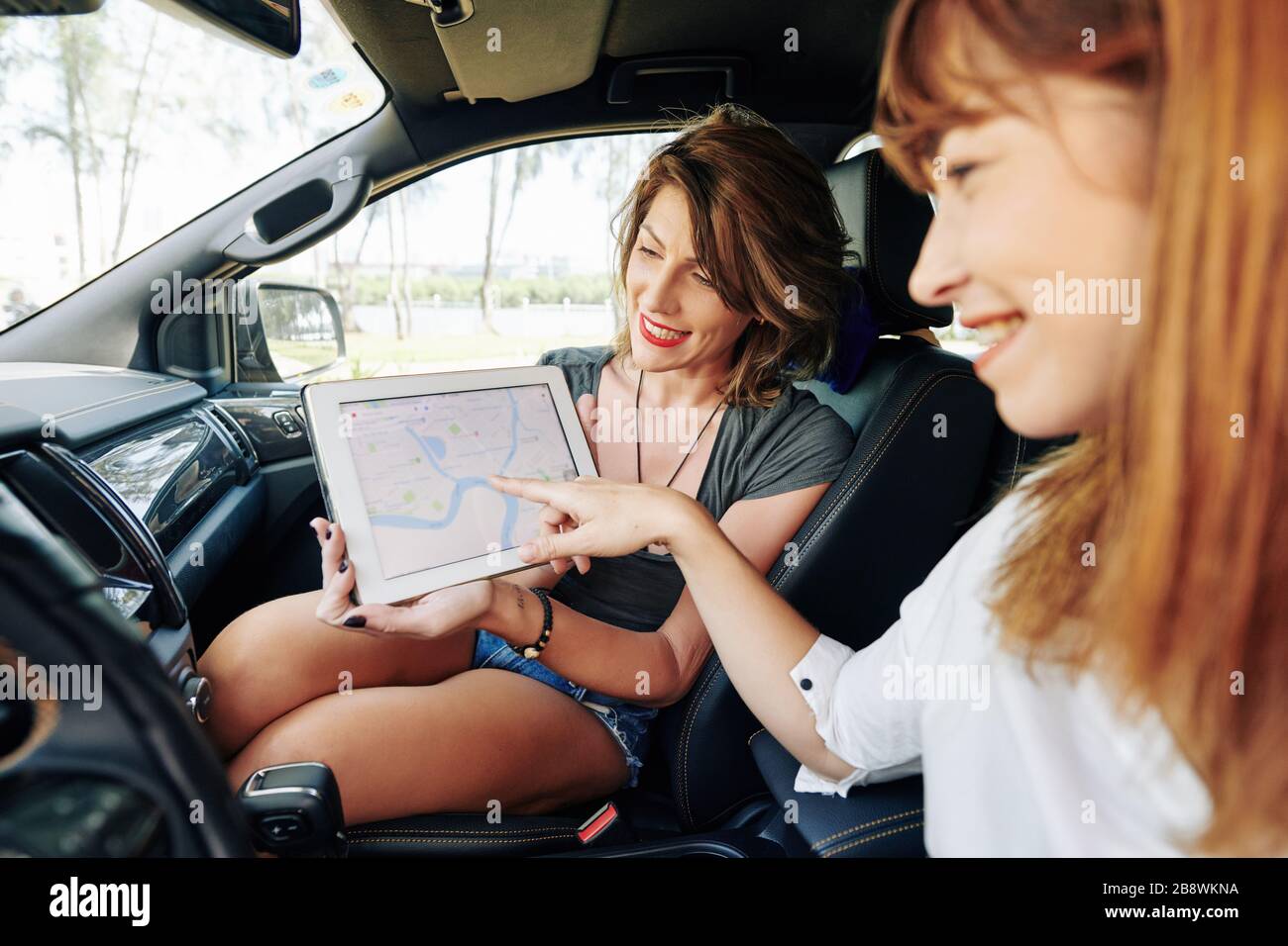 Junge Frau, die an einem beliebigen Ort auf der Karte zeigt, an dem Freunde am Wochenende fahren werden Stockfoto
