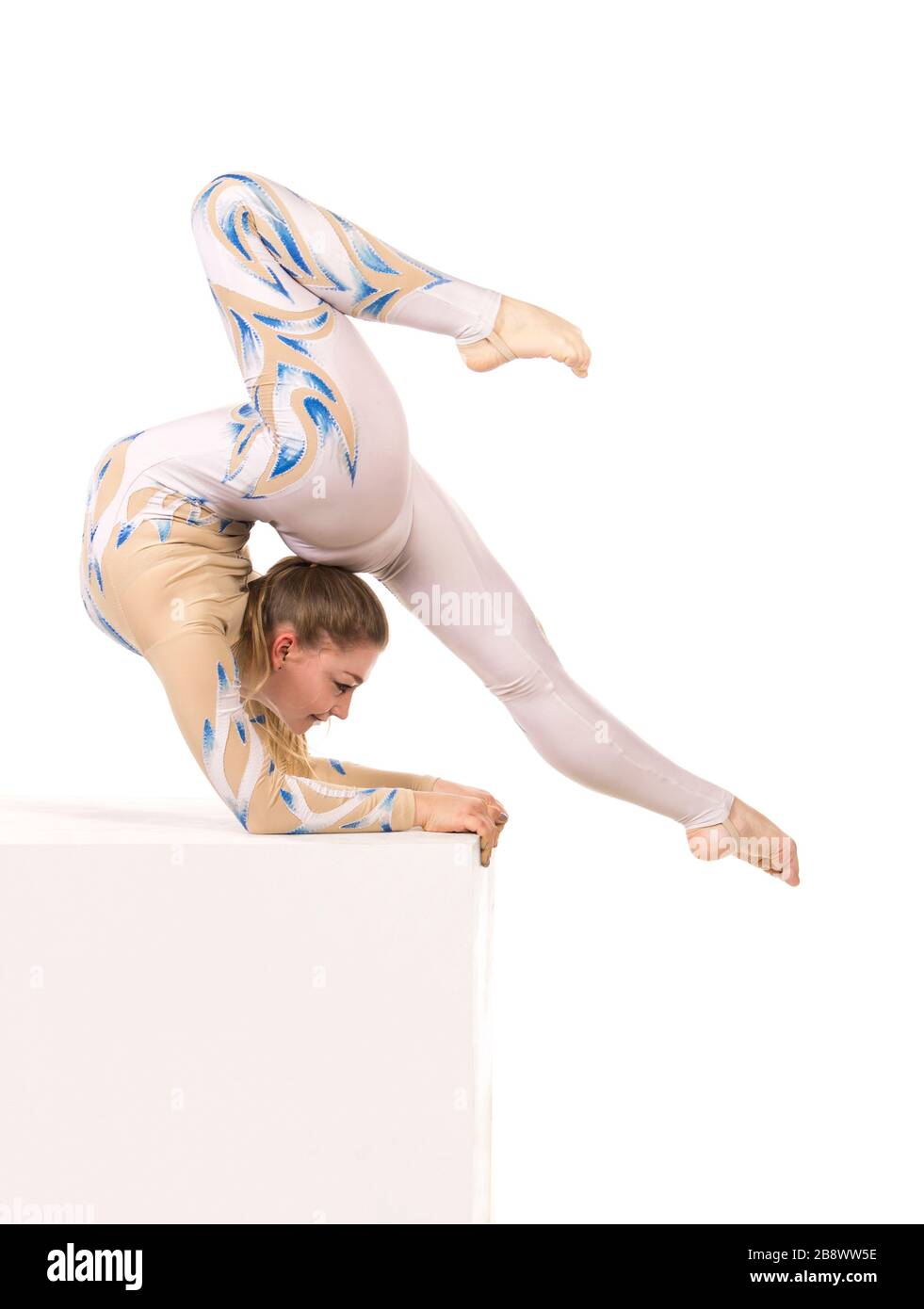Akrobat Turnen, ein junger Zirkuskünstler in einem weißen und blauen Anzug, führt akrobatische Elemente aus. Studio, das ein isoliertes Bild auf weißem Hintergrund abschießt Stockfoto