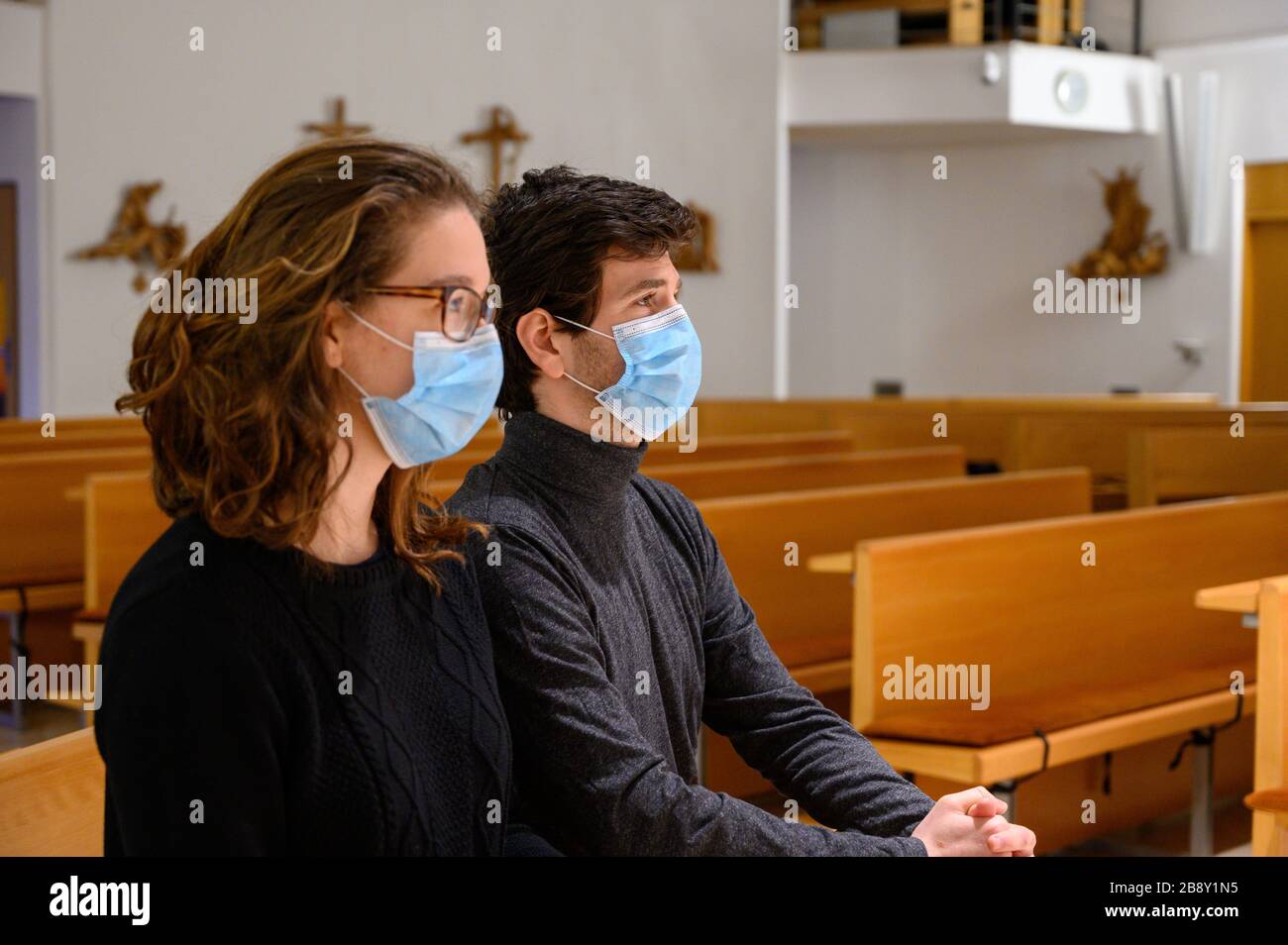 Ein junges Paar in Gesichtsmasken betet während der COVID-19-Pandemie in einer Kirche. Bratislava, Slowakei. Stockfoto