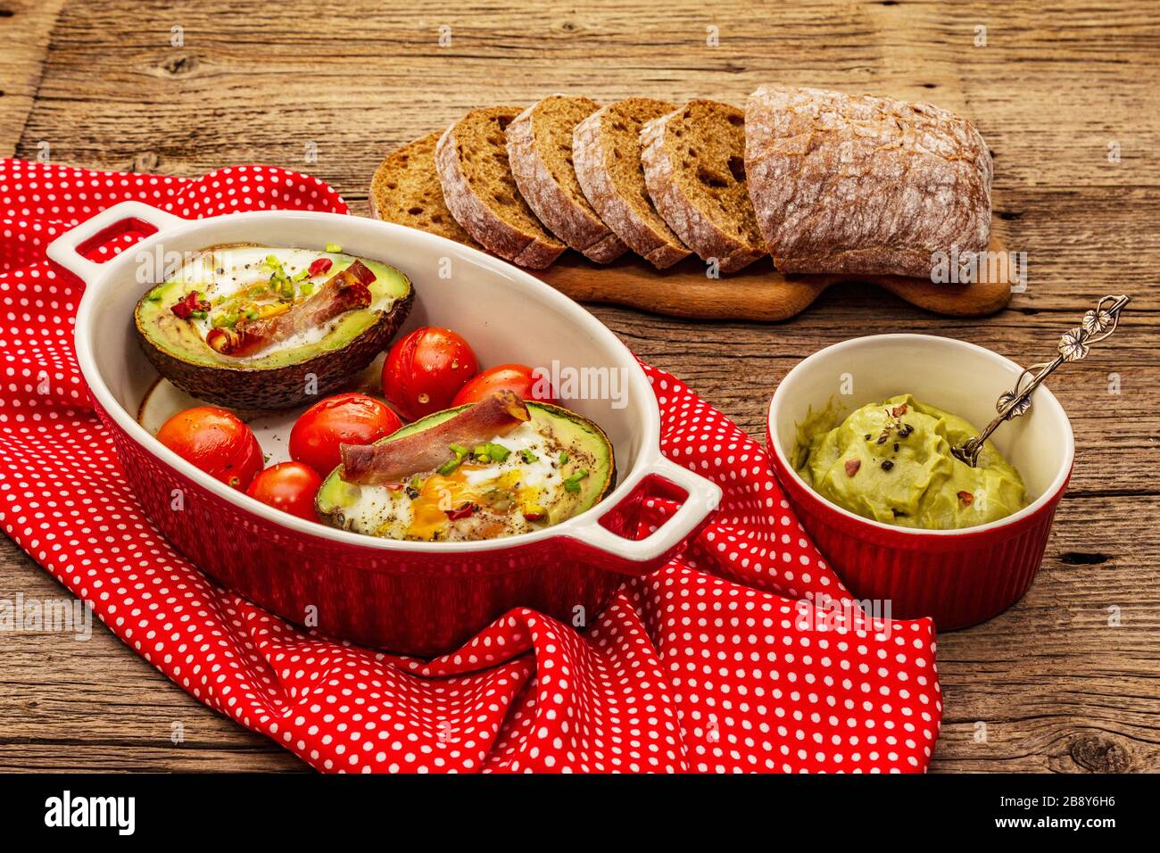 Frühstück am sonnigen Morgen. Gebackene Eier in Avocado-Hälfte, Speck ...
