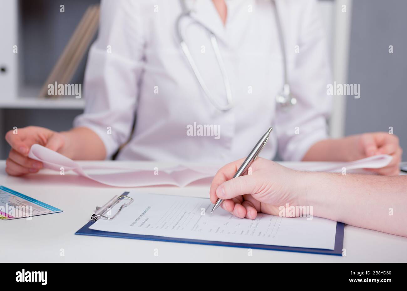 Der Patient füllt den Fragebogen in einer Arztpraxis aus. Stift in der Hand. Die Bildtiefe des Feldes. Stockfoto