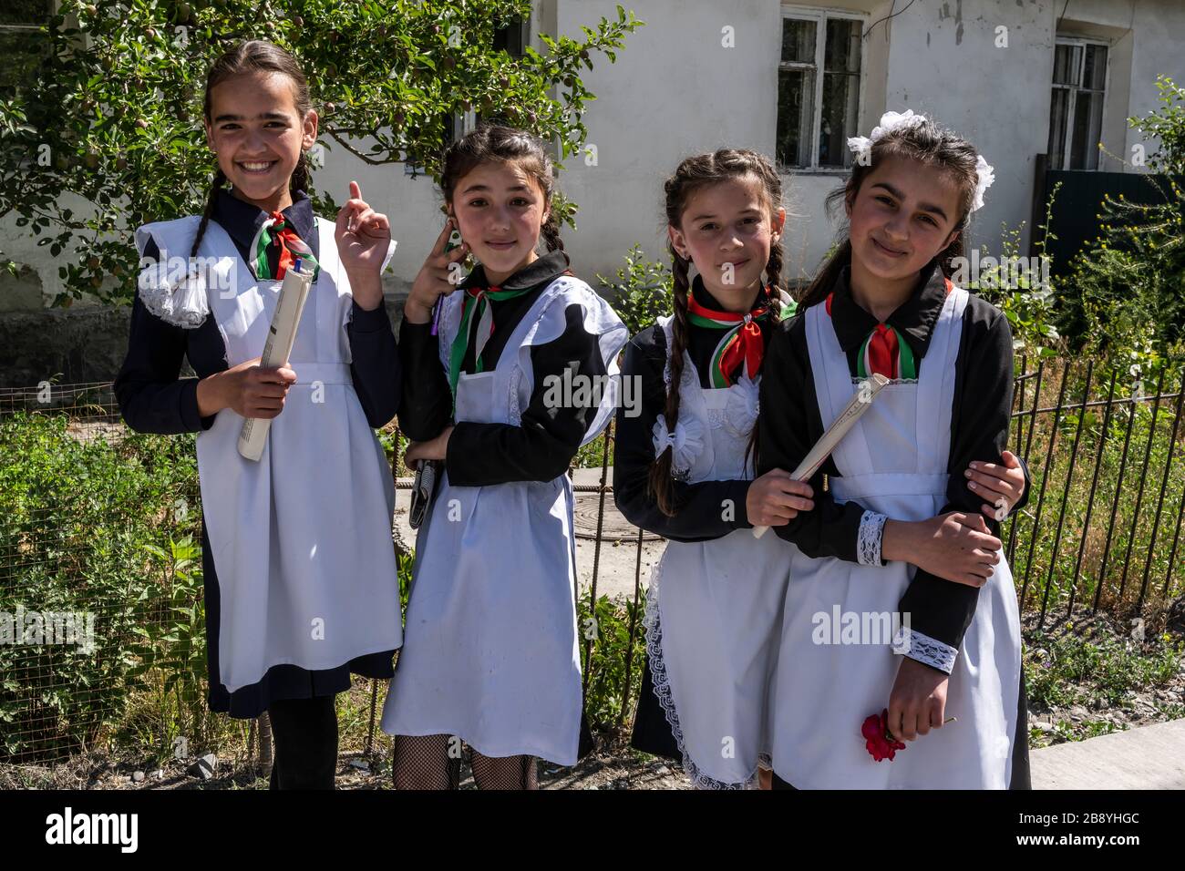 Rushon, Tadschikistan - 17. Juni 2020: Vier Schulkinder, Mädchen, in Schultracht vor der Schule am Pamir-Highway in Tadschikistan. Stockfoto