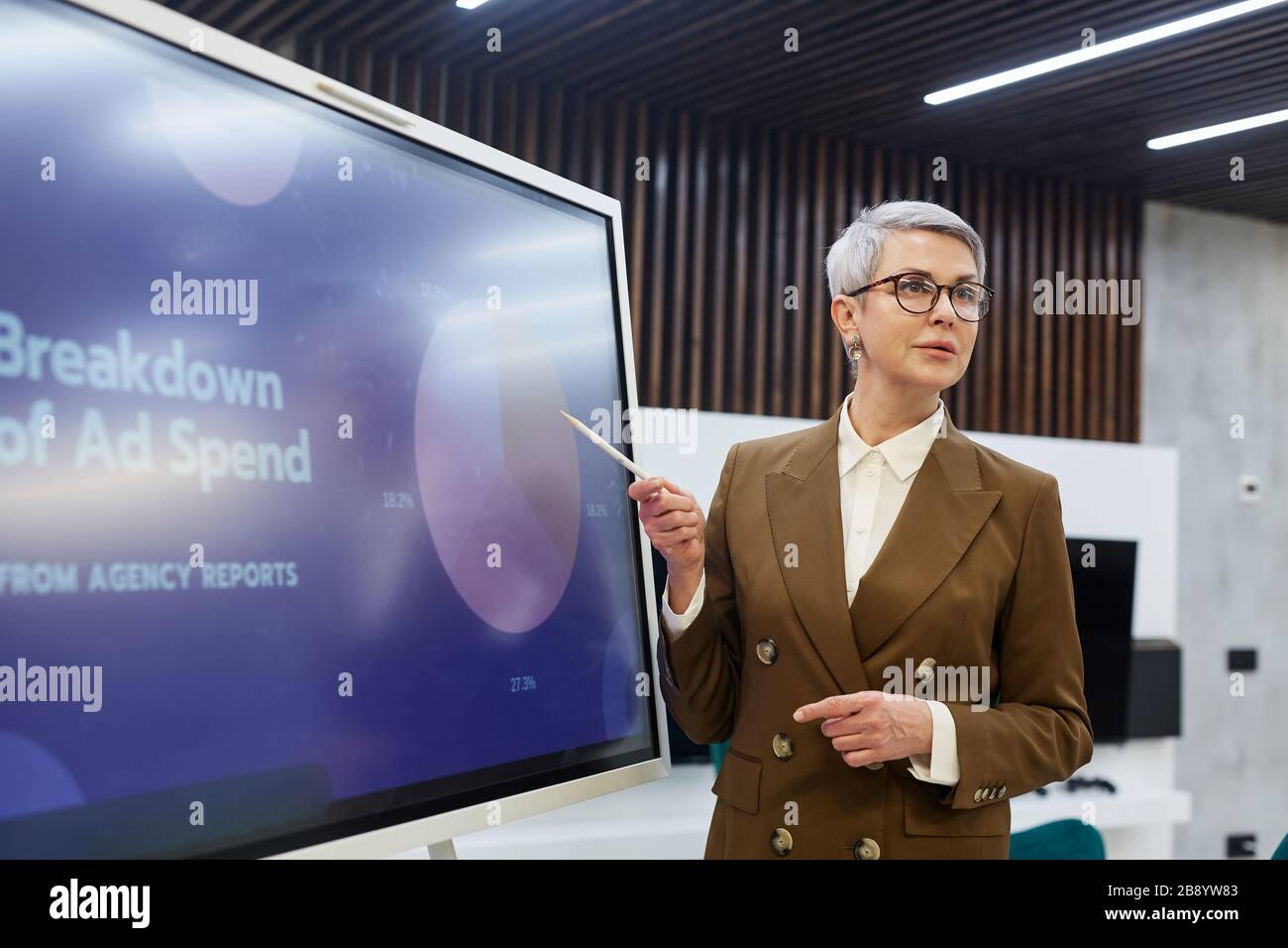 Taille oben Portrait der erfolgreichen reifen Geschäftsfrau, die auf Tortendiagramm zeigt, während sie Präsentation über Marketing und Kopierraum gibt Stockfoto