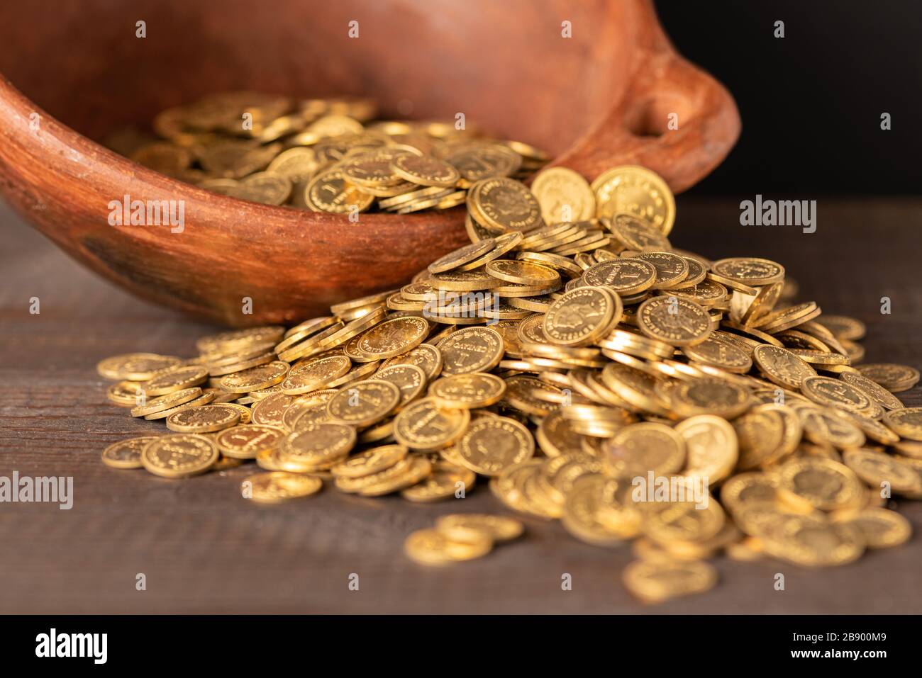 Kaskade kleiner goldener Münzen aus einem Krockentopf Stockfoto