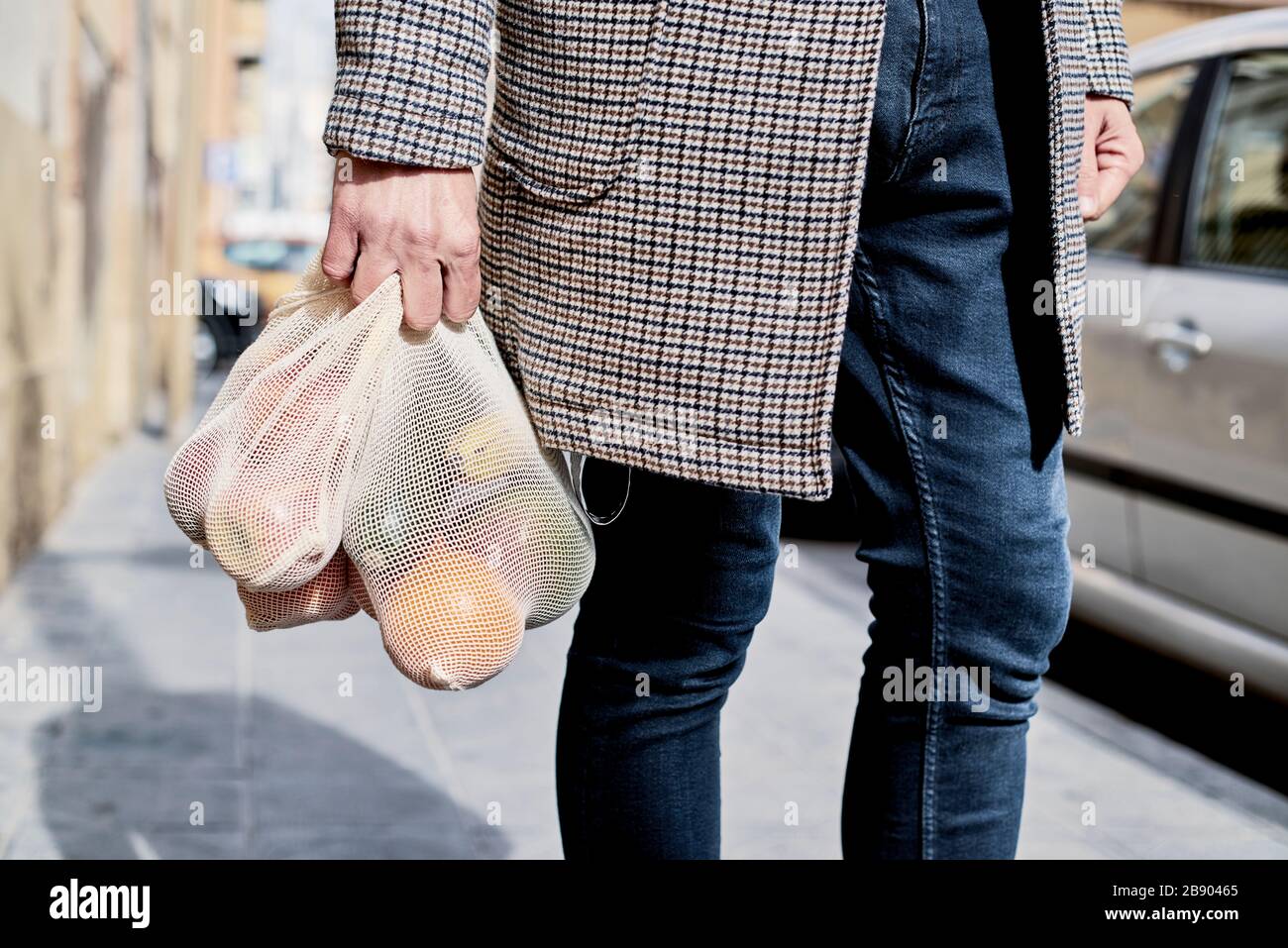 Nahaufnahme eines Mannes auf der Straße, der einige wiederverwendbare Textil-Netztaschen trug, früher zum Kauf von Lebensmitteln in loser Schüttung, voller Obst und Gemüse, als Maßnahme zu Stockfoto