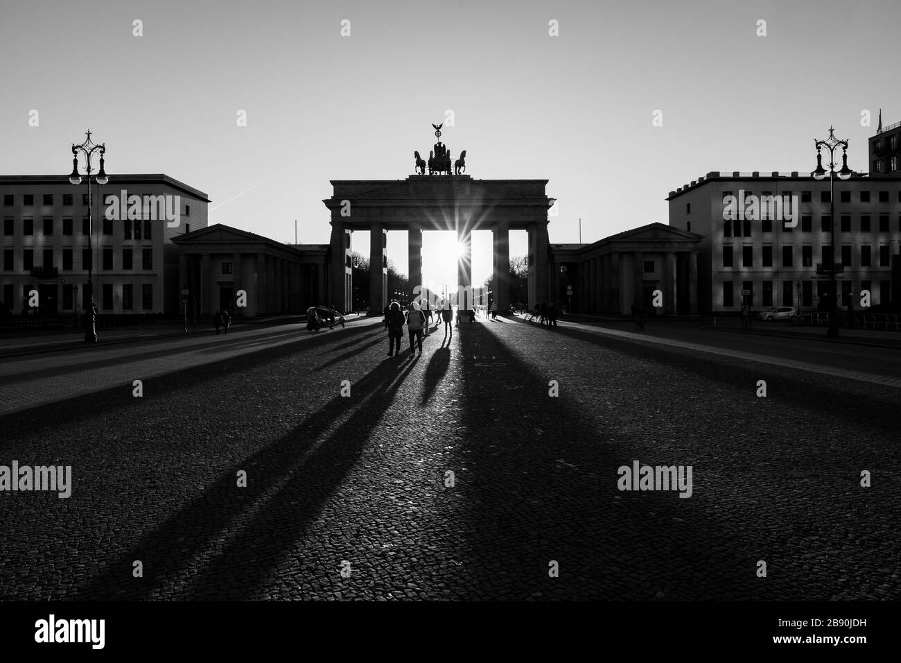 Berlin, Deutschland. März 2020. 22.03.2020, das Brandenburger Ziel in Berlin an einem späten Frühlingssaftstag in der Sonne. Die Sonne scheint durch die Prophylaxe und erzeugt eine besondere Stimmung von Licht und langen Schatten. Wegen der Koronakrise sind in Berlin nur wenige Menschen auf den Straßen und Plätzen. Weltweite Nutzung Credit: Dpa / Alamy Live News Stockfoto