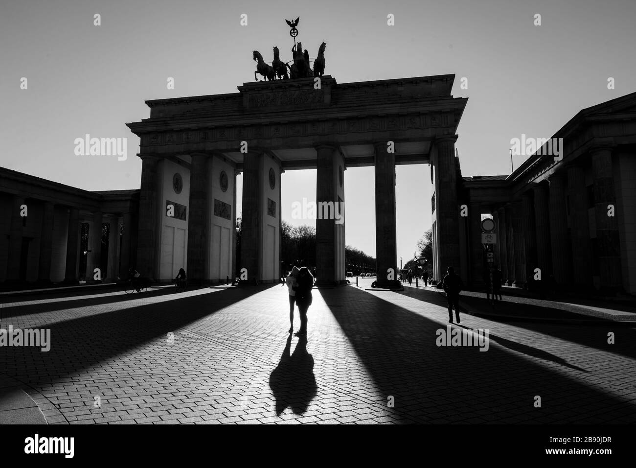 Berlin, Deutschland. März 2020. 22.03.2020, das Brandenburger Ziel in Berlin an einem späten Frühlingssaftstag in der Sonne. Die Sonne scheint durch die Prophylaxe und erzeugt eine besondere Stimmung von Licht und langen Schatten. Wegen der Koronakrise sind in Berlin nur wenige Menschen auf den Straßen und Plätzen. Weltweite Nutzung Credit: Dpa / Alamy Live News Stockfoto