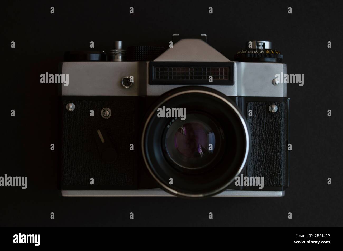 Vintage-Film-Fotokamera auf dem dunklen Hintergrund. Schwarzer Metallrahmen aus Silber und Kunststoff mit Linse Stockfoto