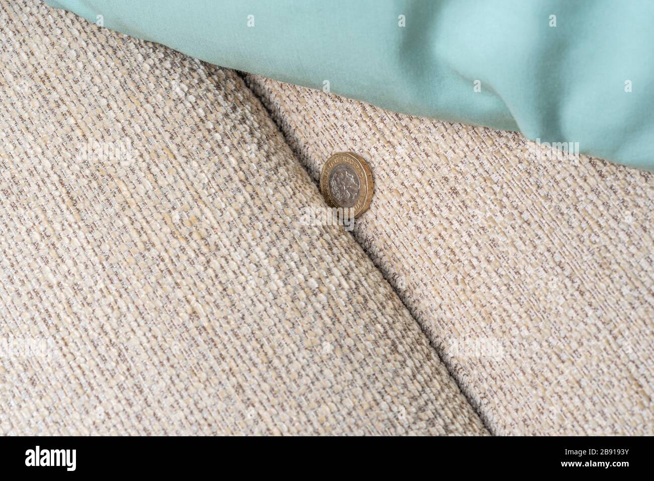 Pound-Münze, die auf der Rückseite eines Sofas herunterfällt. Stockfoto