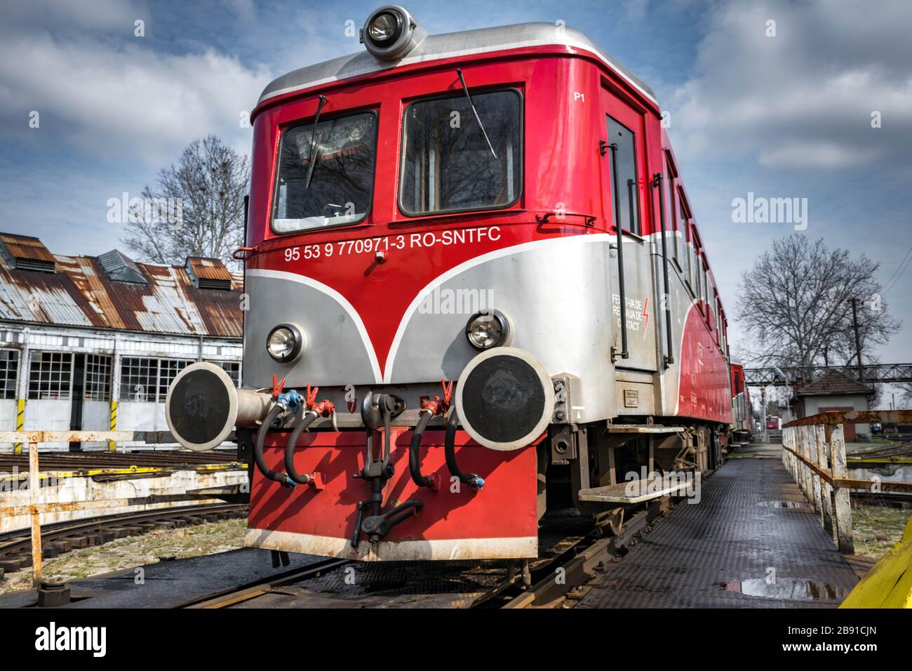 Rote Diesellokomotive, die auf der Bahn fährt. Viele Geländer im Hintergrund Stockfoto