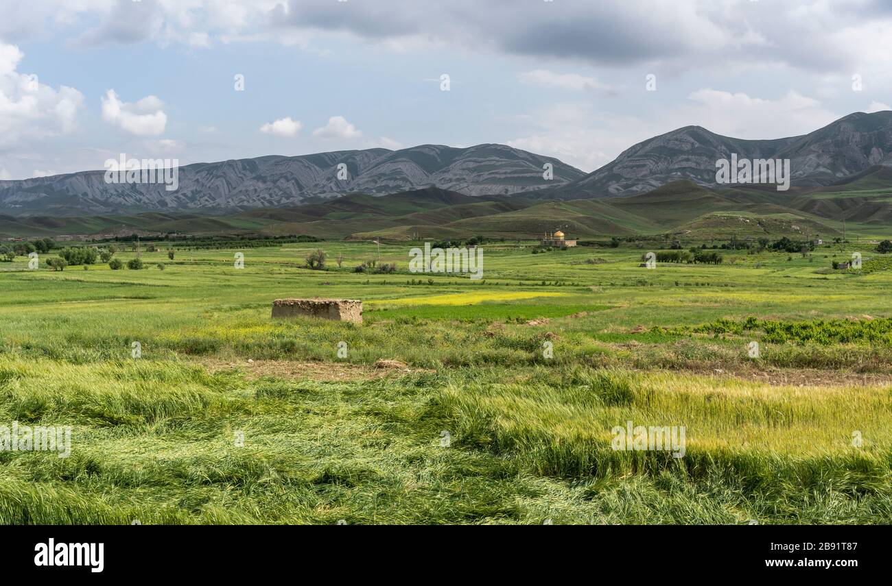 Landschaft in der Nähe von Farooj mit kleinem Dorf in der Provinz Razavi Khorasan mit grünen Feldern und Moschee im Sommer im Iran. Stockfoto