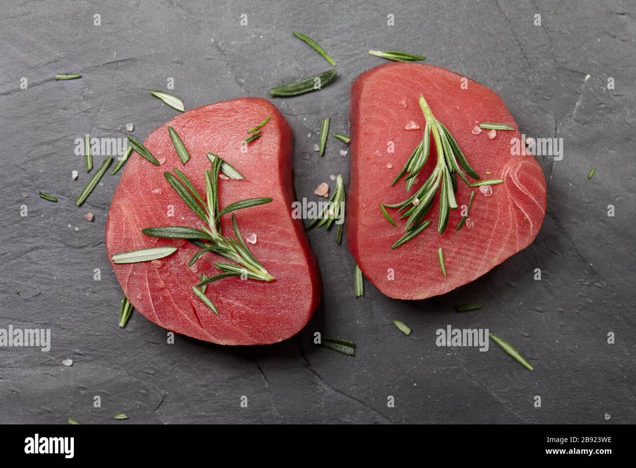 Rohes Thunfischsteak mit Rosmarin auf schwarzem Stein Stockfoto