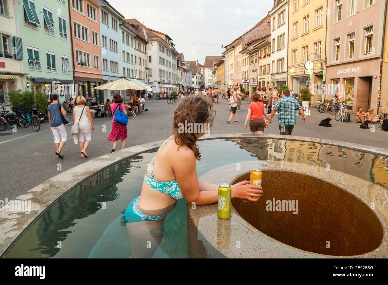 Mylène Jacquemart trinkt und kühlt in einem Brunnen an der Steinberggasse, in der Schweiz, ab. Die drei elliptischen Brunnen auf der Straße, designe Stockfoto