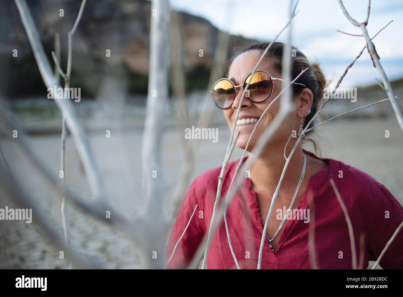 Porträt einer Frau, die Sonnenbrille trägt und bei Sonnenuntergang lächelt. Stockfoto