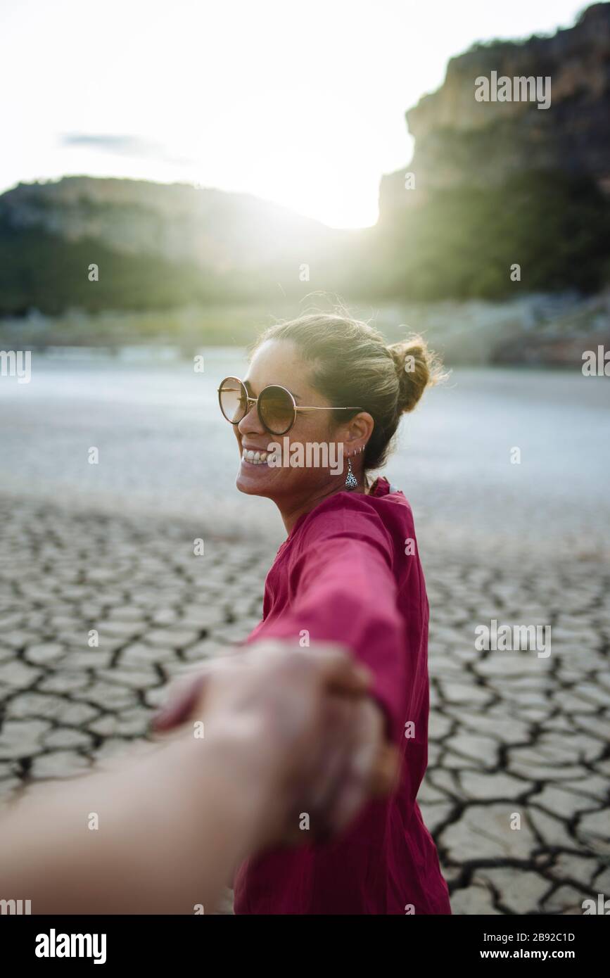 Lächelnde Frau, die ihre Hand für ihren Freund hält und die Kamera anschaut Stockfoto