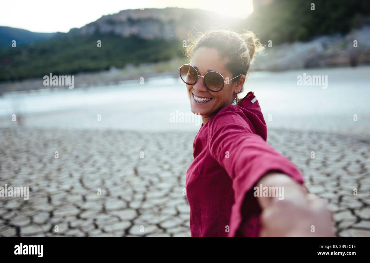 Lächelnde Frau, die ihre Hand für ihren Freund hält und die Kamera anschaut Stockfoto