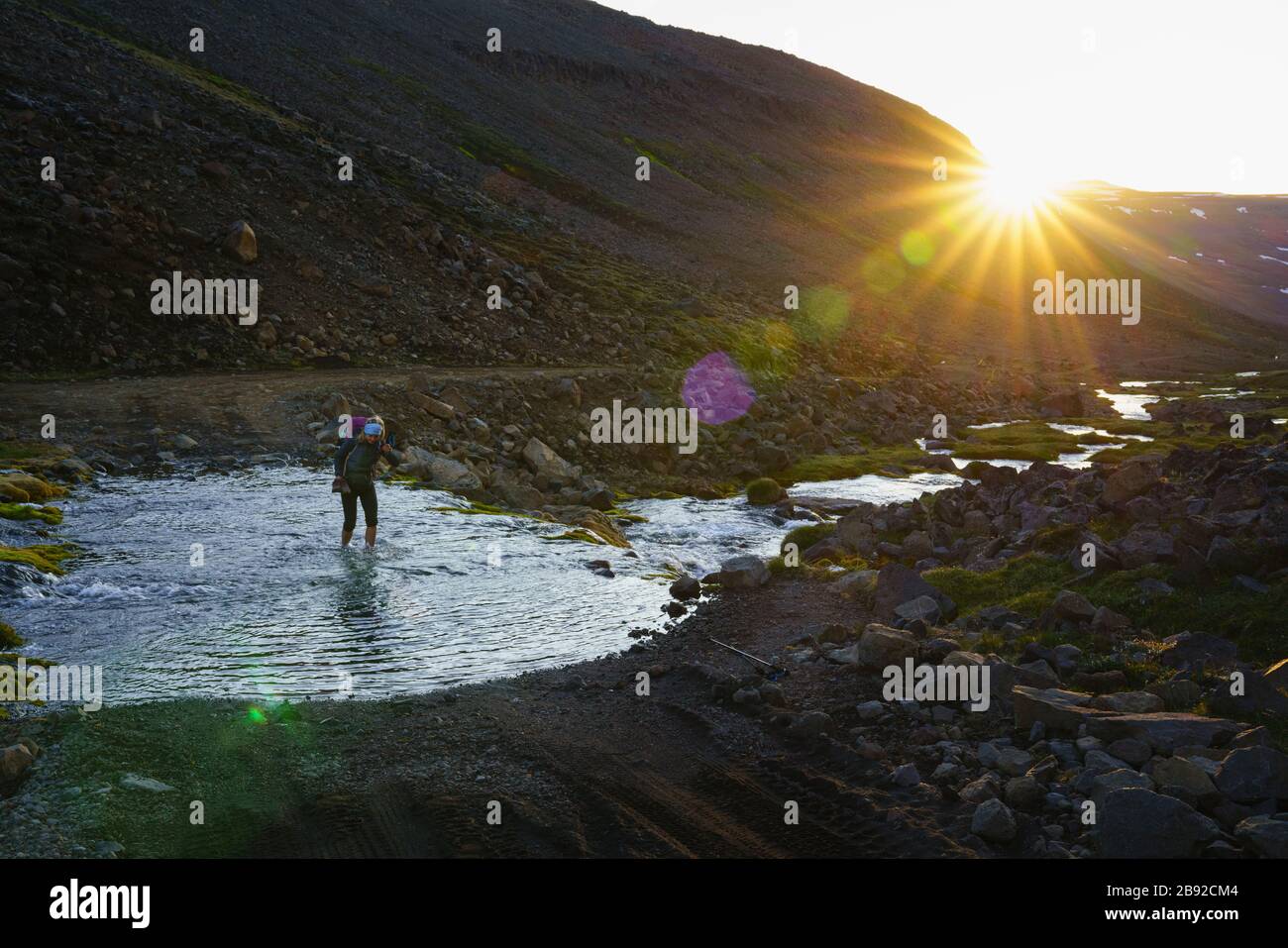 Famale Backpacker Crossing Glacial River In Island Highlands Stockfoto