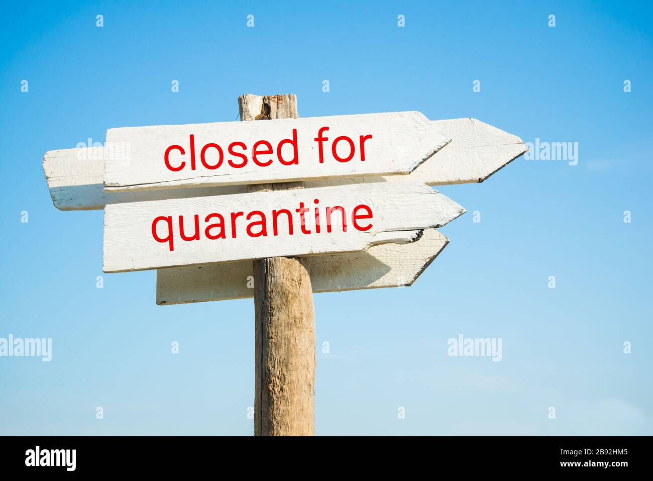 Weiße Holztafel gegen klaren blauen Himmel am sonnigen Tag mit geschlossenem Quarantänetext Stockfoto