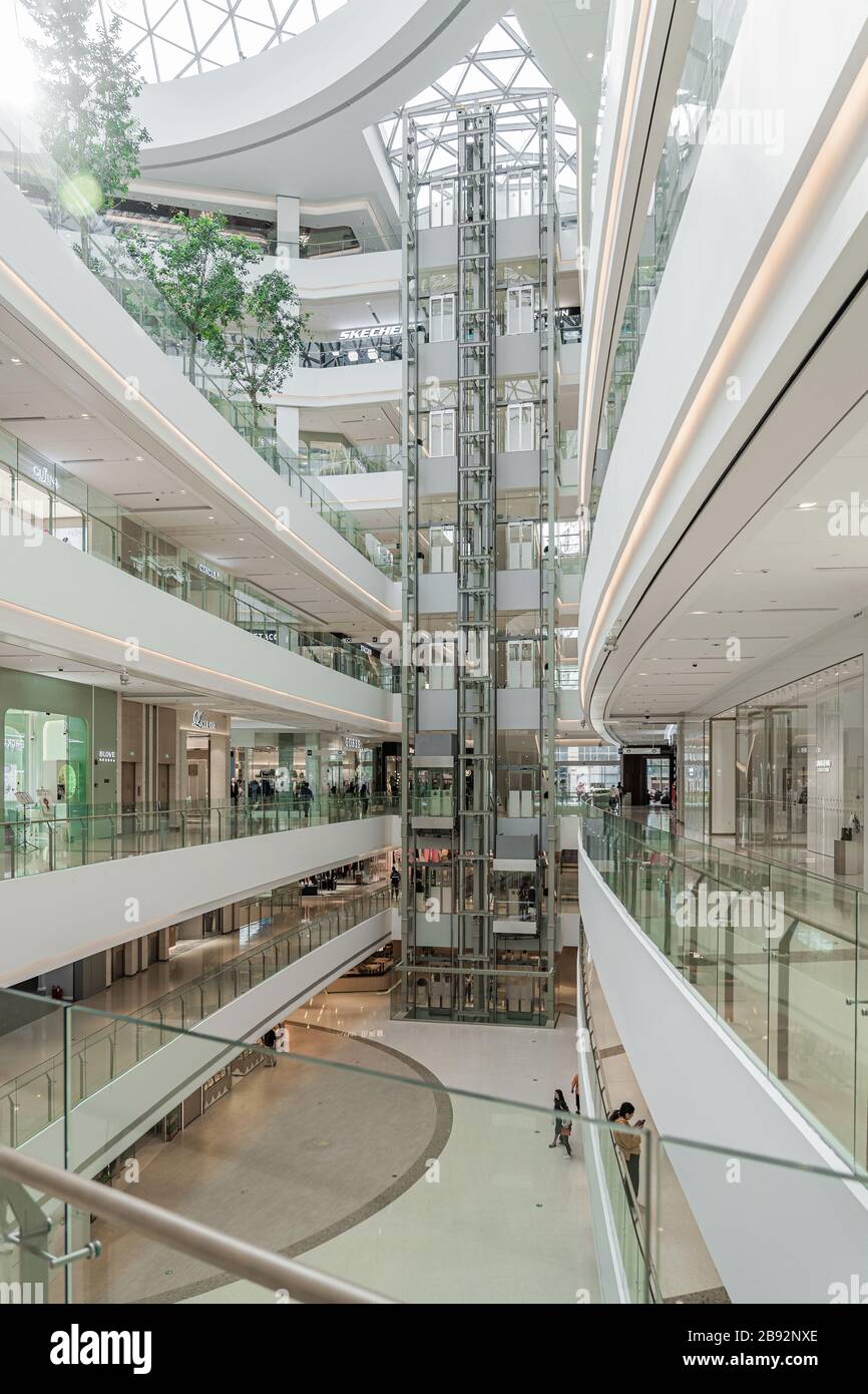 SHANGHAI, CHINA - 10. NOVEMBER 2018. Panorama-Aufzüge im Atrium einer neuen Shopping Mall LuOne Shanghai. Glasaufzüge in White Retail Interior des Stockfoto