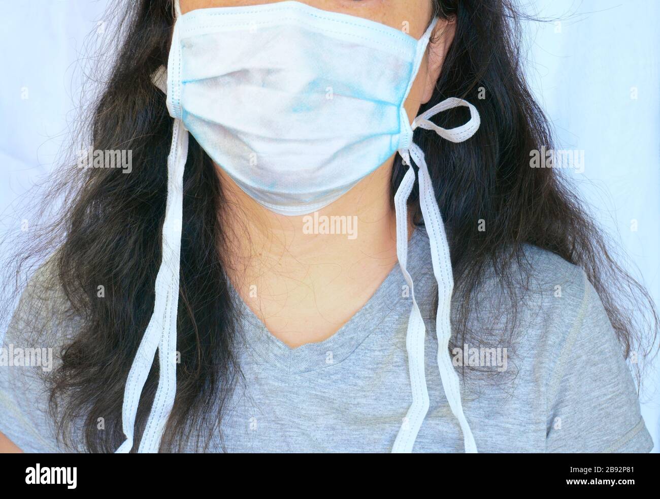 Frau, die während der neuartigen Coronavirus alias Covid-19-Pandemie eine normale präventiive Maske für chirurgische chirurgische chirurgische chirurgische chirurgische Körper trägt. Candid Porträt, Teilgesicht und Körper und langes Haar. Stockfoto