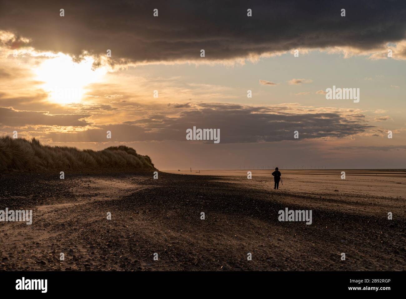 Einsame Figur am Strand in Talacre, Nordwales Stockfoto