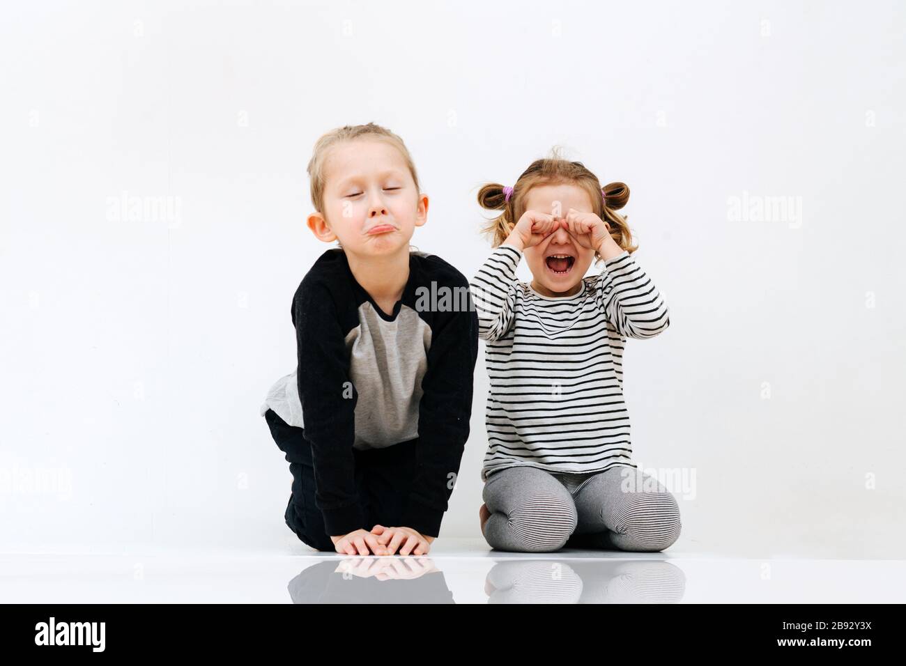 Geschwisternachtsein täuschen vor, stellen Unmut dar und weinten durch Lachen Stockfoto