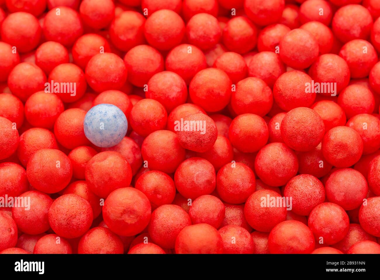 Farbige kleine rote und blaue Polystyrolkugeln. Konzeptionell für Covid-19 Selbstisolation, Krankheitsträger, infizierte Person, isoliert, in der Menge verloren Stockfoto