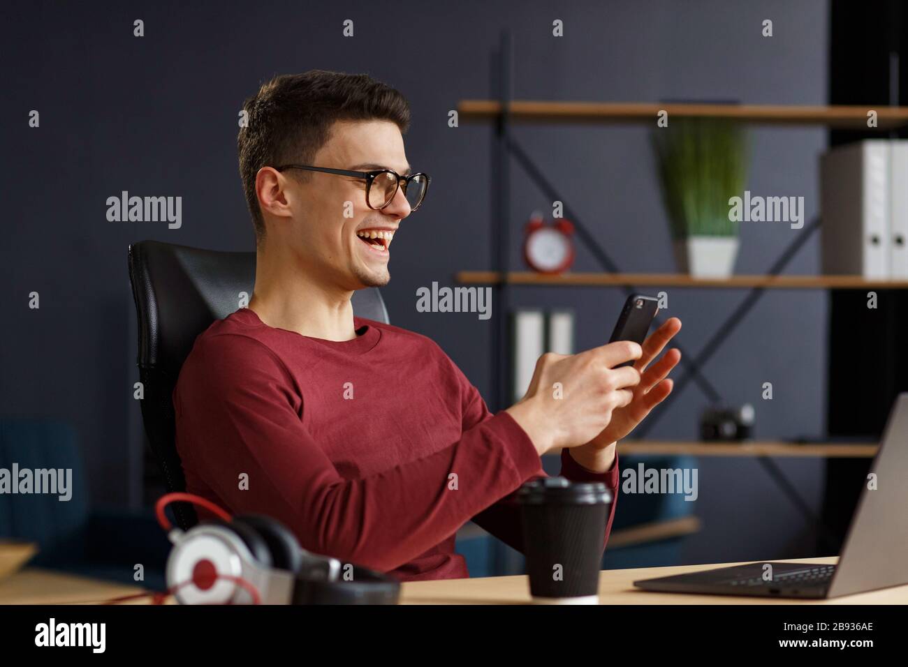 Junger Mann mit Smartphone und Lächeln. Glücklicher Geschäftsmann Stockfoto