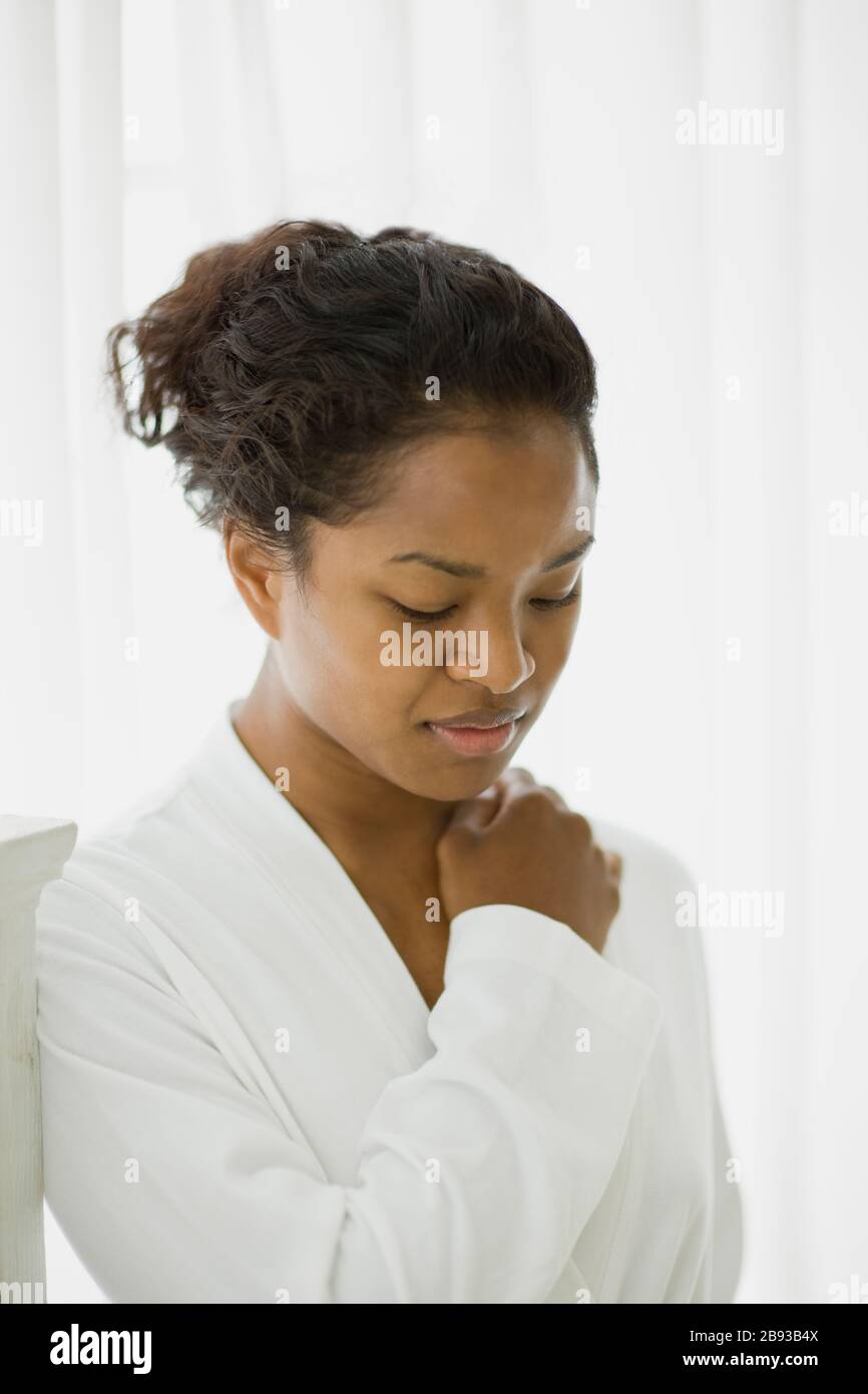 Junge Frau, die während des Tragens einer weißen Robe nach unten blickt. Stockfoto