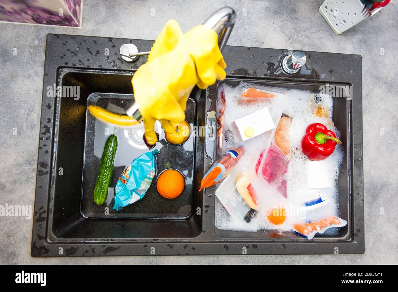 Waschbecken mit gelben Handschuhen und gewaschenen Lebensmitteln Stockfoto