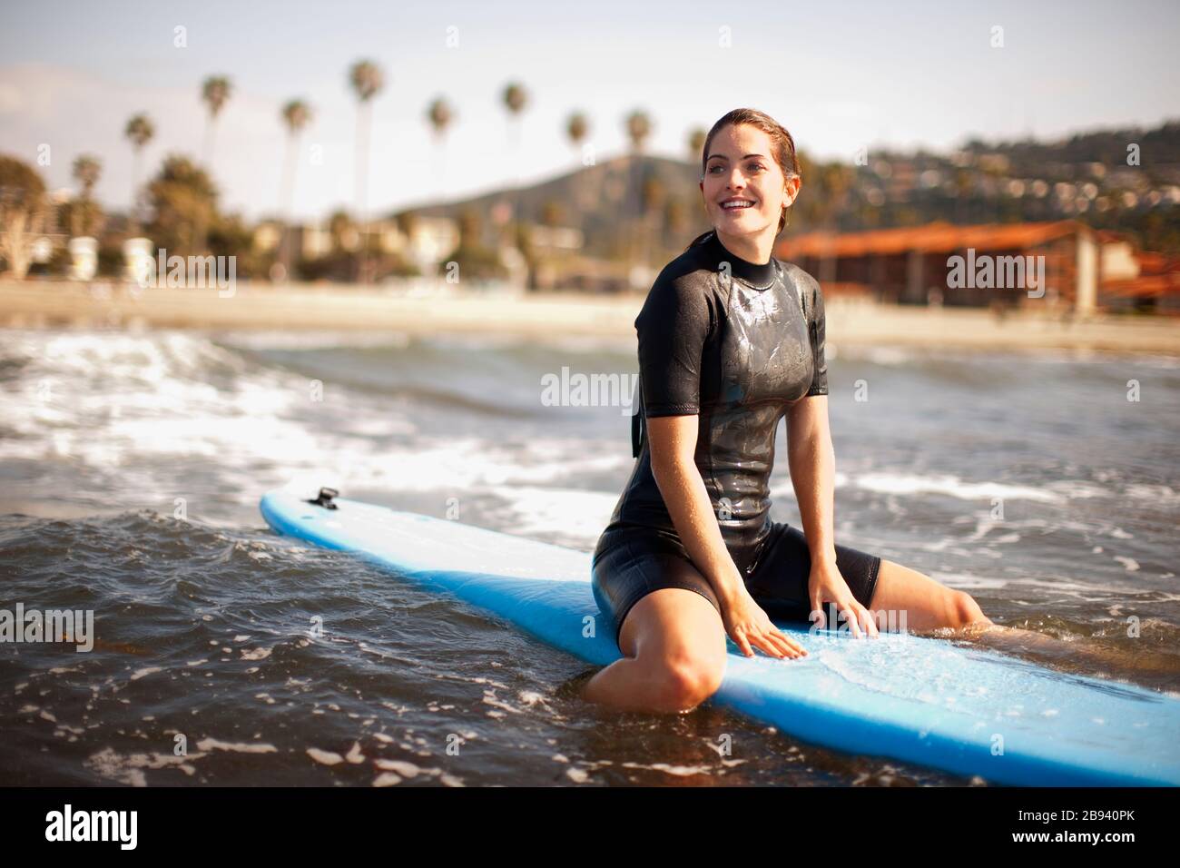 Junge weibliche Surfer sitzen auf Surfbrett, wartet auf eine Welle. Stockfoto