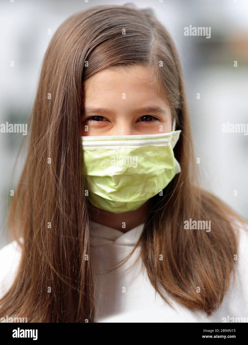 Junge Mädchen mit langen braunen Haaren tragen eine chirurgische Maske, um die Atemwege vor dem Corona-Virus zu schützen Stockfoto