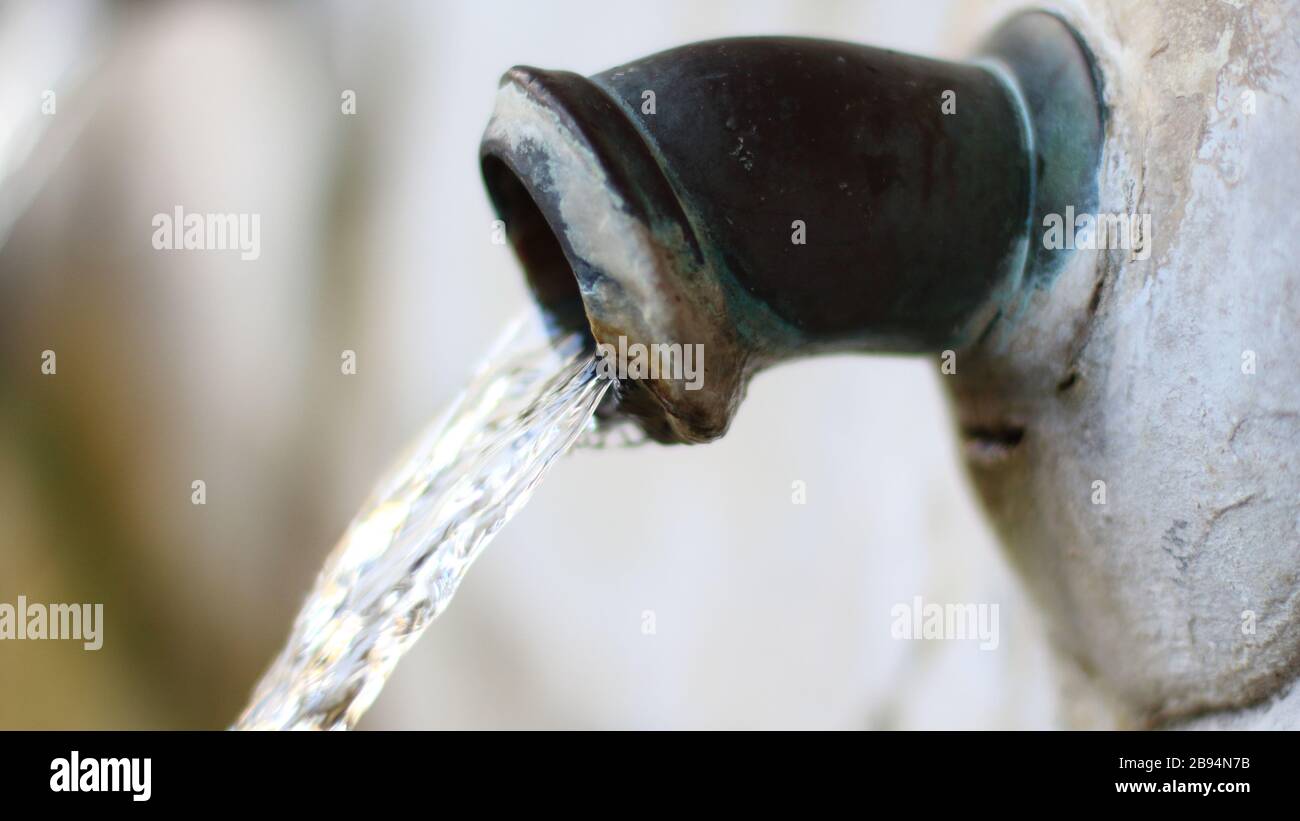 Der Wasserstrahl, der aus dem Wasserhahn des Brunnens kommt Stockfoto