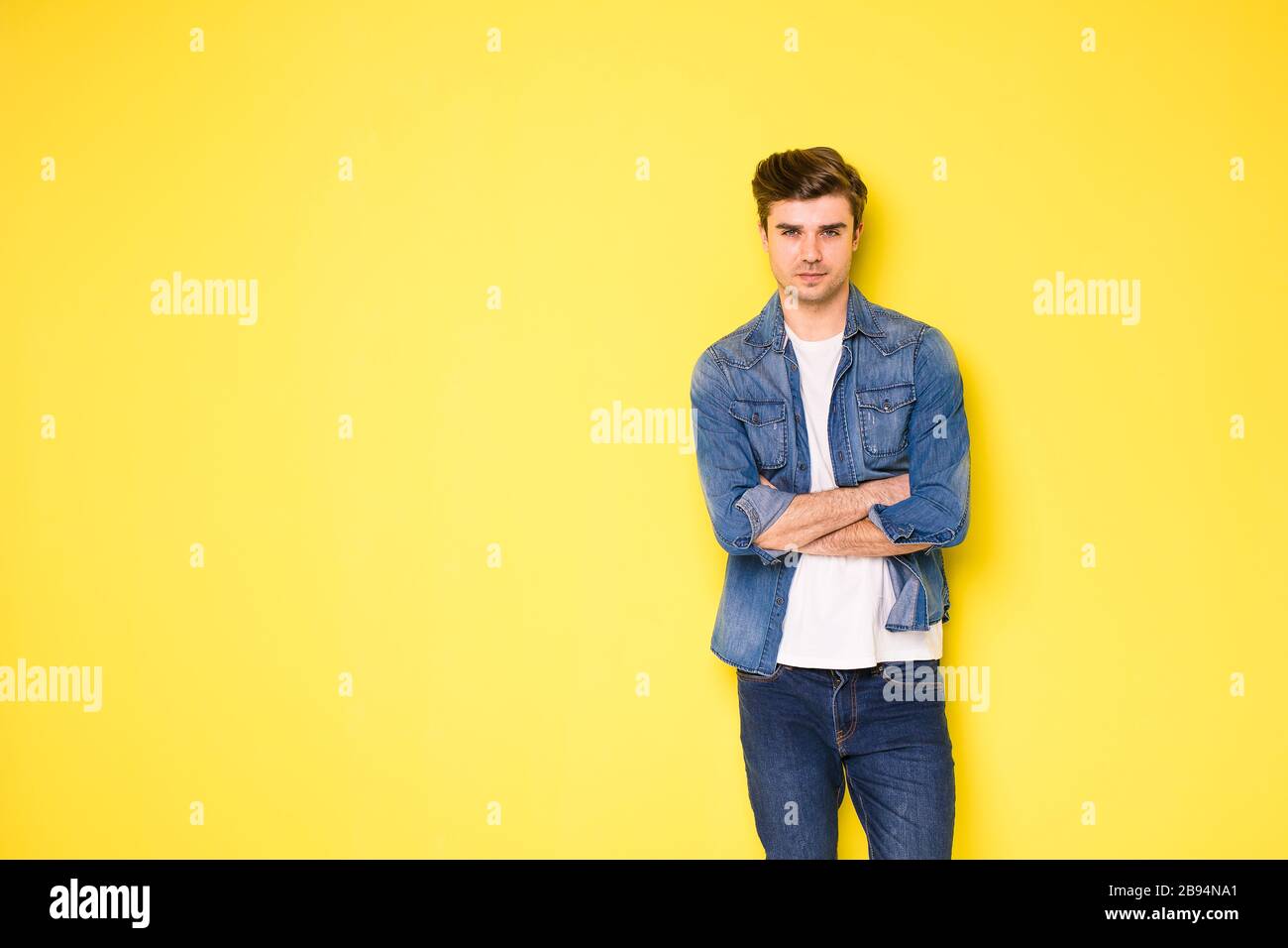 Coole, hübsche junge Männer in Jeans-Outfit, das auf gelbem Hintergrund steht Stockfoto