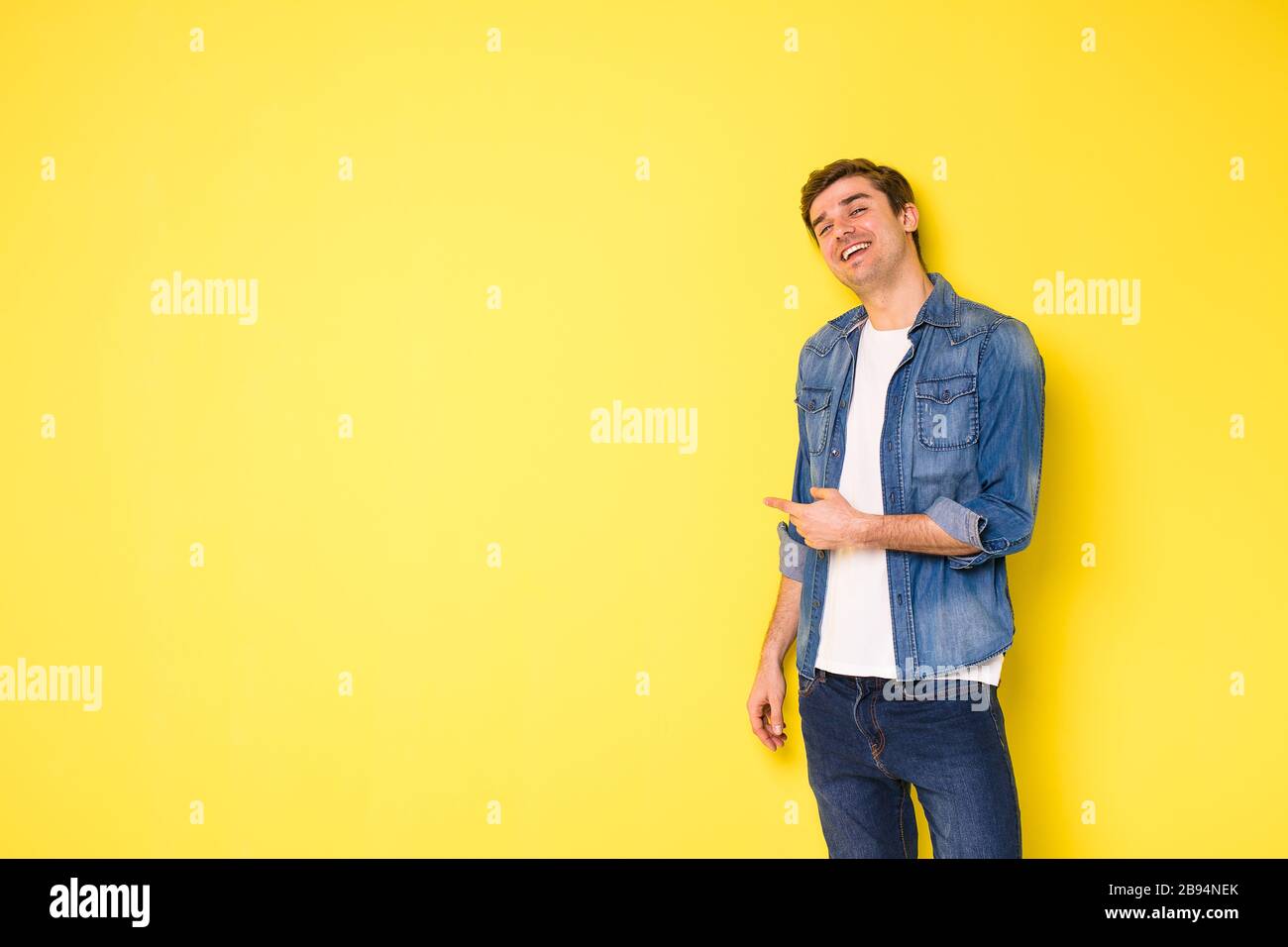 Junge Männer, die auf gelbem Hintergrund stehen und auf eine Seite des Rahmens zeigen oder schauen, freier Platz für Text Stockfoto