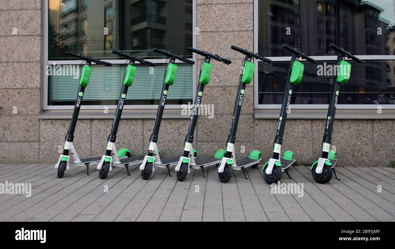 Während eines sonnigen Sommertags im städtischen Stadtzentrum von Helsinki wurden viele Roller mit Elektroverleih in Limette fotografiert. Trendige Art zu bewegen. Helsinki, FI. Stockfoto