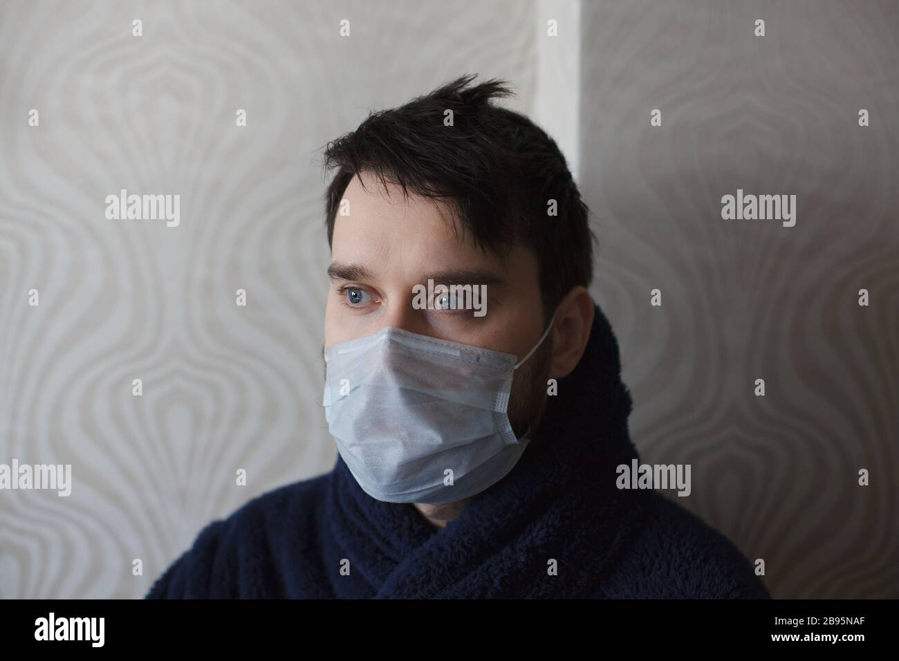 Mann in der Medizin maskiert zu Hause und blickt nach vorne. Vorsicht vor  Coronavirus. Bleiben Sie in Quarantäne Stockfotografie - Alamy