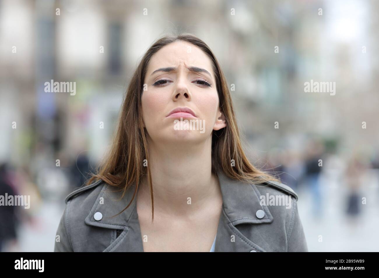 Vorderansicht Porträt einer enttäuschten Frau mit Blick auf die Kamera auf einer Straße in der Stadt Stockfoto