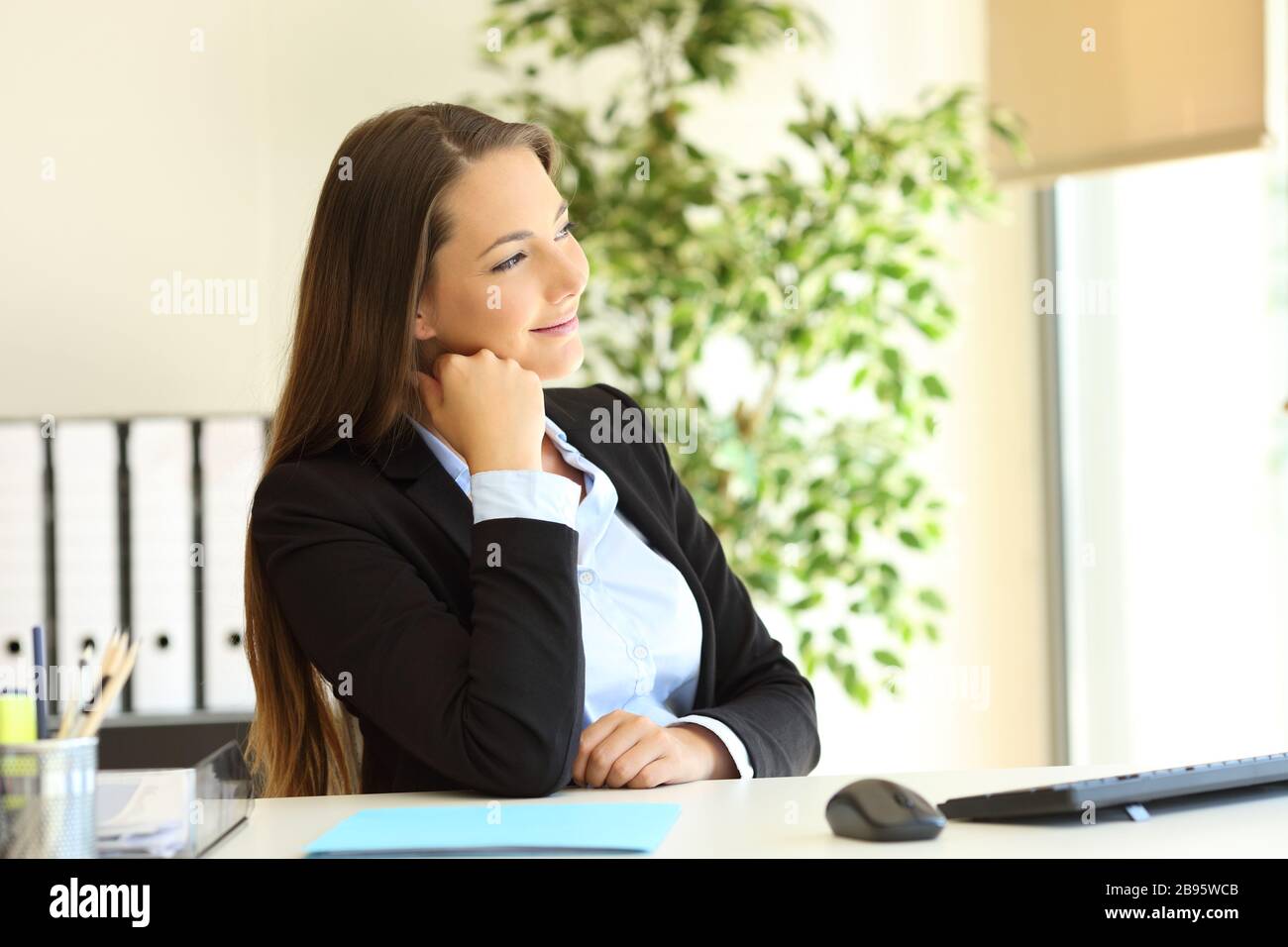 Pensive Führungskraft zufrieden mit dem Blick durch ein Fenster im Büro Stockfoto