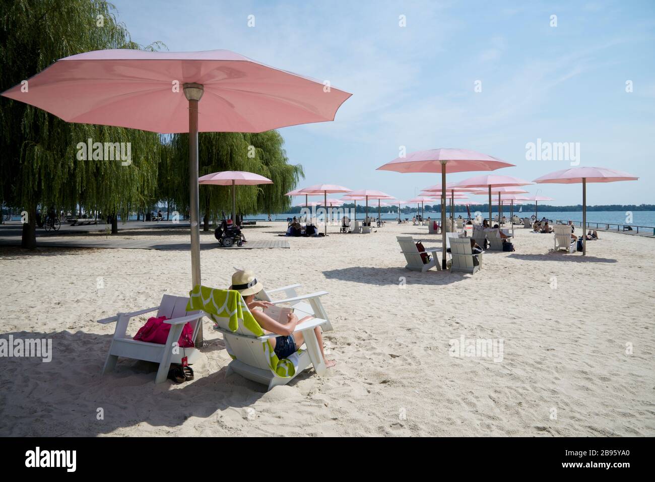 Menschen, die sich am Strand mit einem Sonnenschirm sonnen Stockfoto