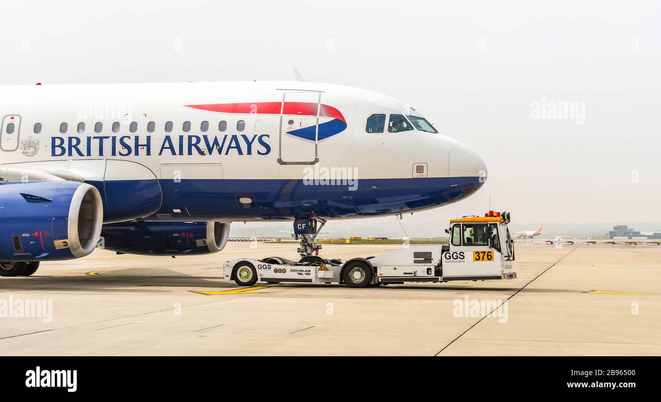 FLUGHAFEN LONDON-GATWICK, ENGLAND - APRIL 2019: British Airways Airbus A319 wird vom Terminal durch einen Schlepper am Flughafen London-Gatwick zurückgedrängt Stockfoto