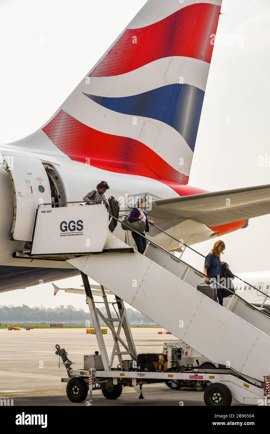 FLUGHAFEN LONDON-GATWICK, ENGLAND - APRIL 2019: Passagiere, die einen Airbus der British Airways nach der Ankunft am Flughafen London-Gatwick aussteigen Stockfoto